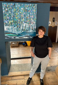 Artist Diya Wen poses in front of her large semi-abstract cityscape